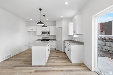 Kitchen with visible vents, light wood-style flooring, white cabinetry, and stainless steel appliances