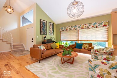 living area with light wood-type flooring, stairway, and high vaulted ceiling