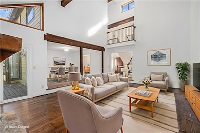 Living room with wood finished floors, a towering ceiling, french doors, and stairs