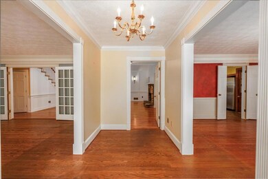 Hall with a wainscoted wall, crown molding, stairw