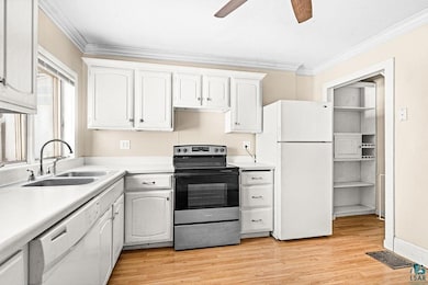 Kitchen with white appliances, ornamental molding, a sink, ceiling fan, and light countertops