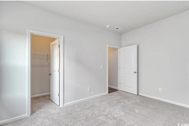 Unfurnished bedroom featuring light carpet, a walk