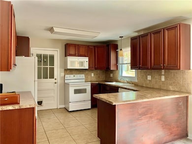 Kitchen with white appliances, a peninsula, a sink