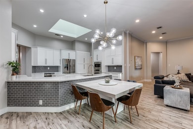 Kitchen with a skylight, white cabinets, tasteful
