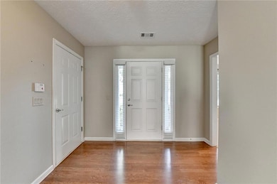Entryway with wood finished floors, a textured ceiling, and baseboards