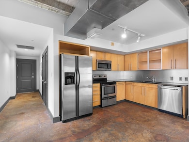 Kitchen with open shelves, appliances with stainless steel finishes, dark countertops, and track lighting