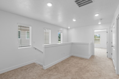 Empty room featuring light colored carpet, a textured ceiling, and recessed lighting