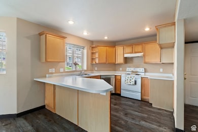 Kitchen featuring open shelves, light brown cabinets, white range with electric stovetop, light countertops, and a peninsula