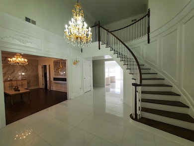 Staircase with a chandelier, a high ceiling, tile patterned flooring, a decorative wall, and crown molding