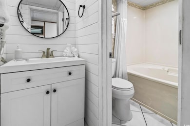 Full bath with light tile patterned flooring, vanity, and shower / bath combination with curtain