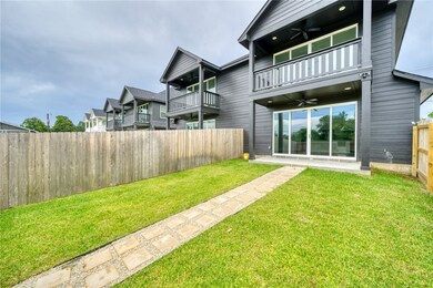 Fenced backyard with a balcony and a ceiling fan