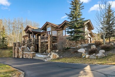 Chalet / cabin featuring stairway, stone siding, a balcony, board and batten siding, and asphalt driveway