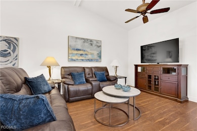 Living room with ceiling fan, wood finished floors, beam ceiling, and high vaulted ceiling