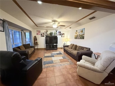 Living room with light tile patterned floors, a textured ceiling, and a ceiling fan