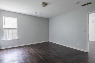 Spare room featuring dark wood-style flooring and baseboards