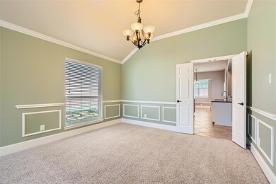 Carpeted spare room featuring a notable chandelier, crown molding, sink, and vaulted ceiling