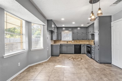 Kitchen featuring gray cabinetry, healthy amount of natural light, light tile patterned floors, stainless steel electric range oven, and a textured ceiling