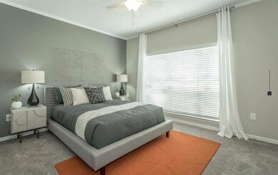 Carpeted bedroom with ornamental molding and a ceiling fan