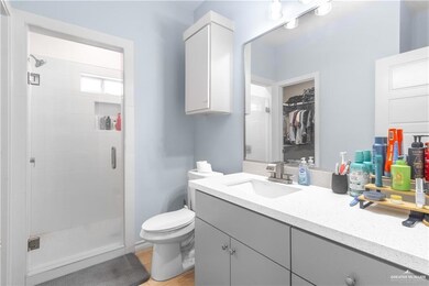 Full bathroom with a stall shower, vanity, a spacious closet, toilet, and wood finished floors