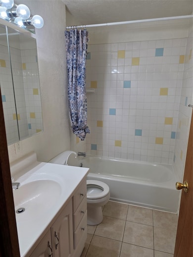 Full bathroom with shower / tub combination, vanity, light tile patterned flooring, a textured wall, and a textured ceiling