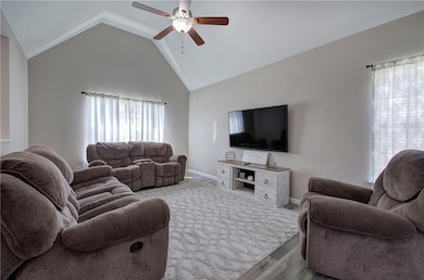 Living area featuring ceiling fan, wood finished floors, vaulted ceiling, and baseboards