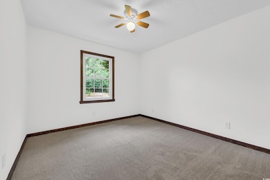Carpeted empty room with baseboards and a ceiling fan