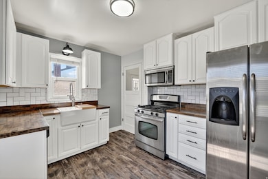 Kitchen with stainless steel appliances, backsplash, and white cabinets