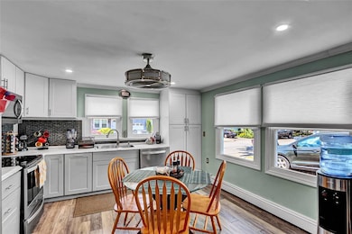 Kitchen featuring appliances with stainless steel finishes, a baseboard heating unit, tasteful backsplash, light countertops, and light wood-style floors