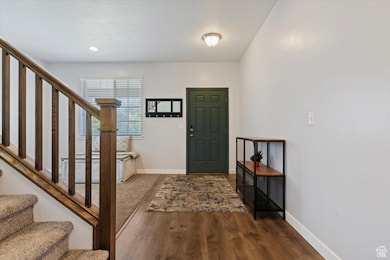 Foyer entrance with stairway, dark wood-style floors, and recessed lighting