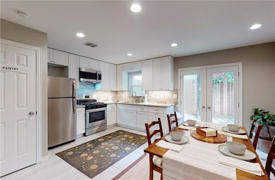 Kitchen featuring french doors, a sink, white cabi