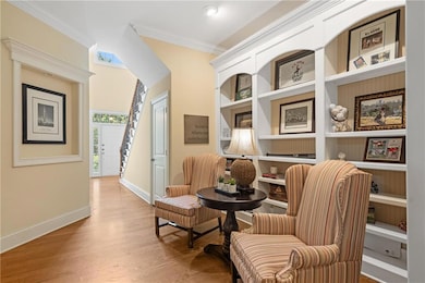 Sitting room with ornamental molding, wood finished floors, and built in features