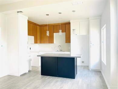 Kitchen featuring white cabinets, light wood-type flooring, sink, decorative light fixtures, and a center island