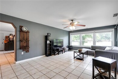 The living room is spacious and features tons of natural light, tile flooring, and a newer ceiling fan.