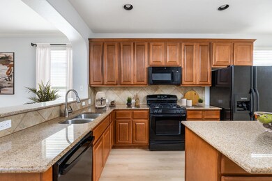 Kitchen with black appliances, brown cabinetry, l
