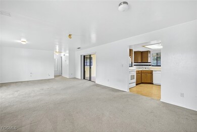 Unfurnished living room with tan colored carpet and baseboards