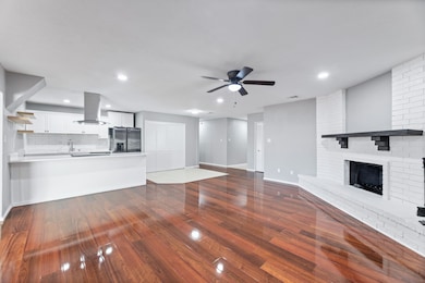 Unfurnished living room with ceiling fan, dark wood-type flooring, recessed lighting, and a brick fireplace