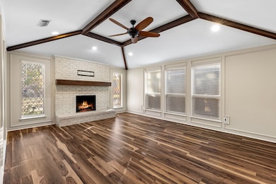 Unfurnished living room featuring a ceiling fan, dark wood-style floors, and a brick fireplace