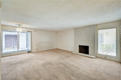 Unfurnished living room featuring a textured ceiling, light carpet, and a fireplace