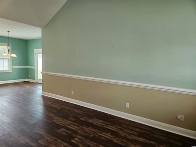 Unfurnished room featuring dark wood finished floors, a chandelier, and lofted ceiling