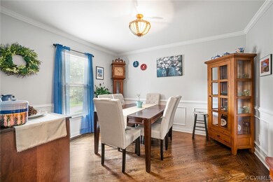Dining room w/ HW floors and a chandelier.