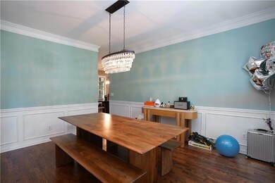 Dining space featuring radiator heating unit, ornamental molding, dark wood-type flooring, a wainscoted wall, and a chandelier