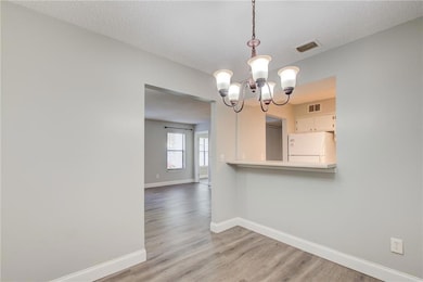 Unfurnished dining area featuring visible vents, baseboards, and an inviting chandelier
