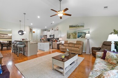 Living area featuring lofted ceiling, ceiling fan, light wood-style flooring, and recessed lighting