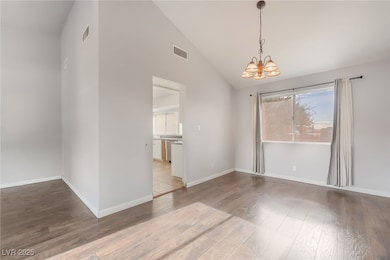 Unfurnished dining area featuring high vaulted ceiling, light wood-style floors, and a chandelier