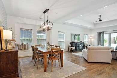 Dining space featuring hardwood / wood-style flooring, a raised ceiling, and ceiling fan with notable chandelier