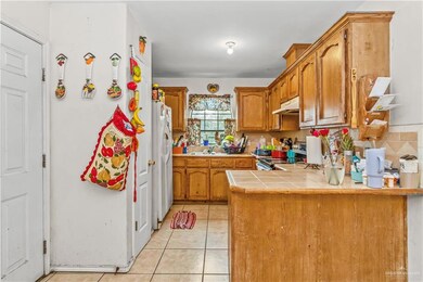 Kitchen with tasteful backsplash, light tile patterned floors, kitchen peninsula, electric stove, and white refrigerator