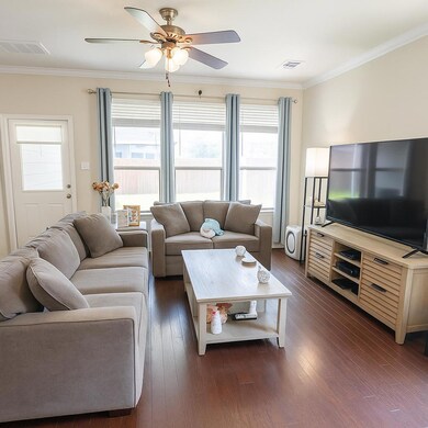 Living area with ceiling fan, dark wood-style flo