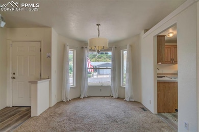 Unfurnished dining area featuring light colored carpet and a chandelier