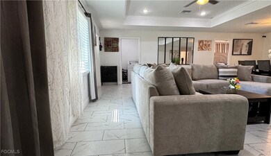 Living room with ornamental molding, a tray ceiling, light marble finish flooring, recessed lighting, and washer / clothes dryer
