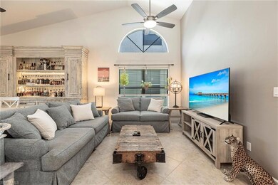 Living area featuring arched window, ceiling fan, light tile patterned flooring, and high vaulted ceiling